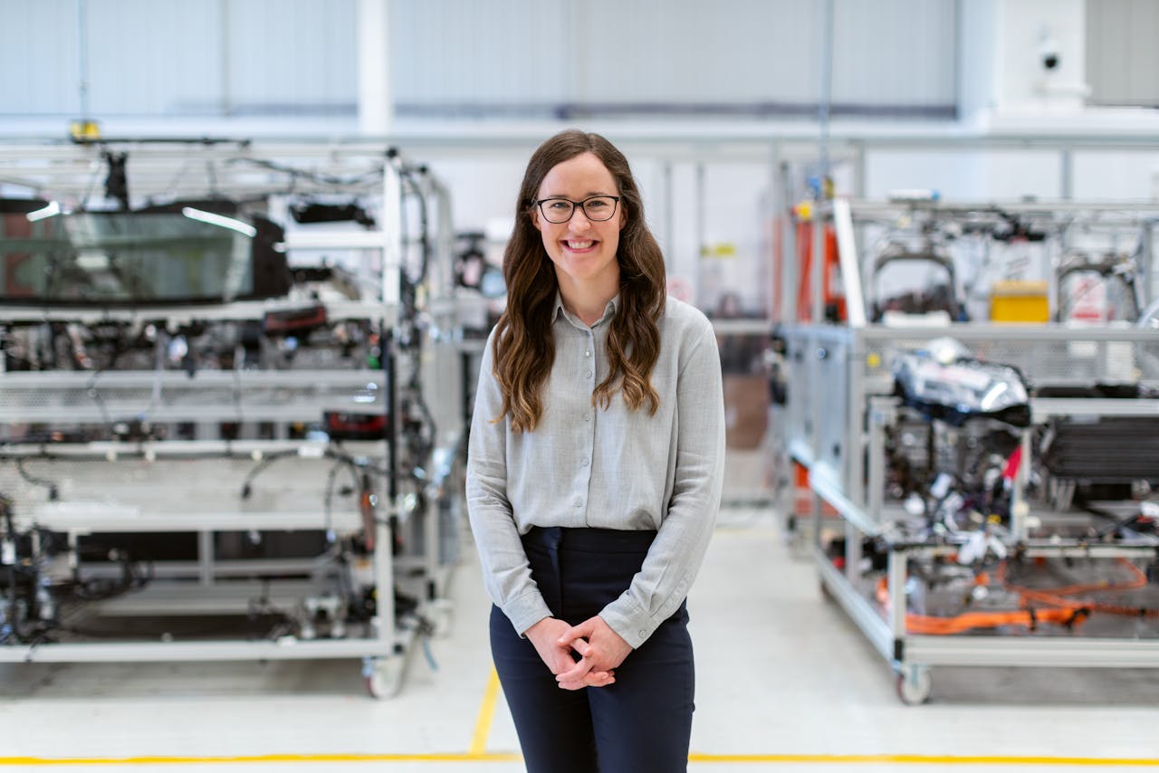 Smiling woman engineer standing confidently in a modern industrial workshop setting.