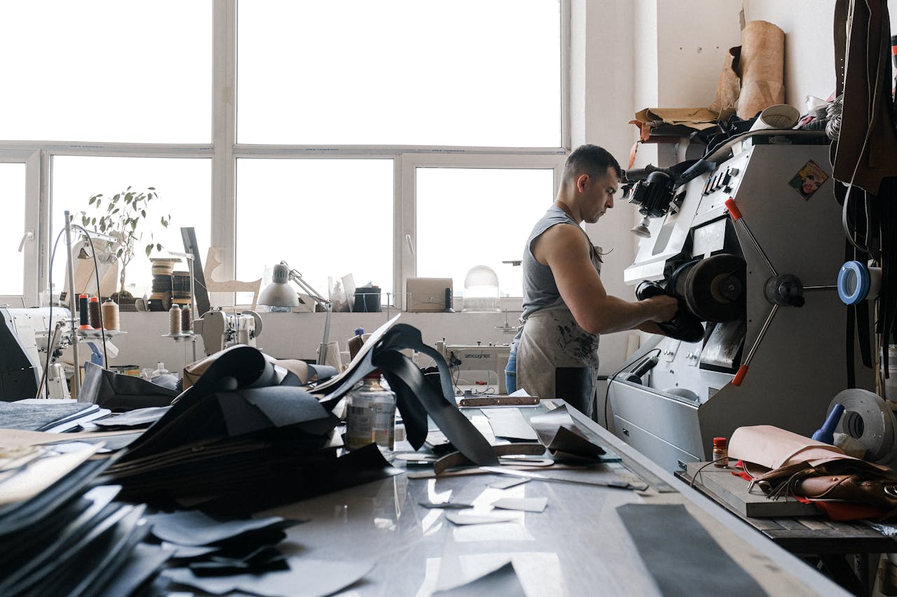 A craftsman working with industrial machinery in a leather workshop, focused and detailed.