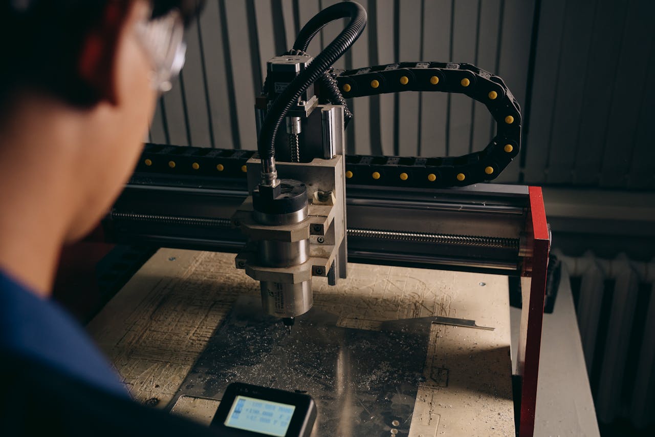 A close-up shot of a CNC machine operating in a workshop with a technician nearby.